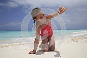 Kneeling girl showing a crab shes collected on the beach