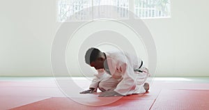 Kneeling judoka saluting on the judo mat