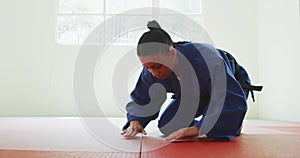 Kneeling judoka saluting on the judo mat