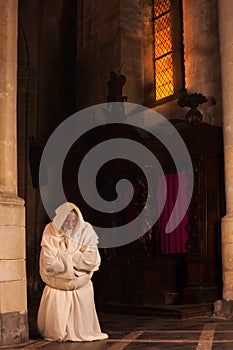 Kneeling monk in dark church