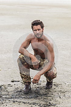 Kneeling Shirtless Soldier on the Beach Sand