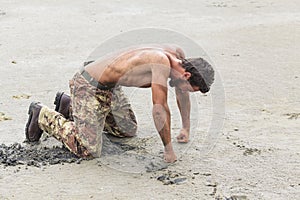 Kneeling Shirtless Soldier with Fists on Ground photo