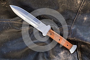 Knife assault dagger for wilderness life on a worn leather black jacket