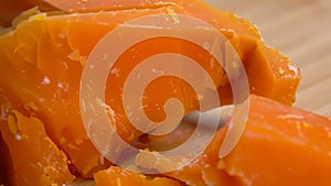 A knife breaks off a piece of hard Mimolette cheese