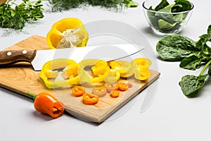 Knife and chopped yellow peppers on cutting board