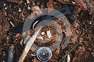 Knife and compass lie on ground in forest. Concept of survival in a wild forest area.