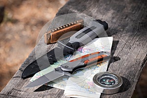 Knife, compass and map on a wooden table. Travel concept.