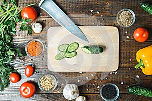 Knife, cucumbers paprika tomatoes and garlic lie on a wooden background