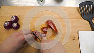 Knife cuts red bell pepper on wooden cutting board. Clip. Cutting core in sweet pepper on wooden cutting board. Remove