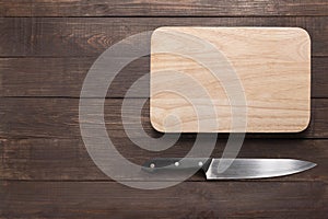 Knife and cutting board on the wooden background