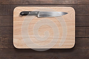 Knife and cutting board on the wooden background