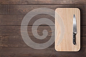 Knife and cutting board on the wooden background