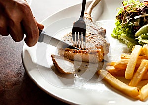 Knife cutting grilled pork chops steak Close up, Pork chop steak with salad and french fries