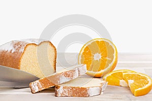 Knife is cutting a lemon cake with some orange fruits on a wooden table, isolated on white