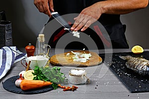 Knife cutting onion. Sliced vegetables on wooden board. Ingredient for Stuffed Fish with Vegetables