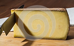 Knife cutting a piece of Comte a famous French cheese