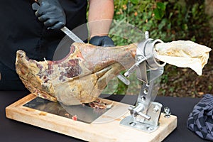 Knife cutting serrano chef man hand slicing of italian dry cured ham prosciutto