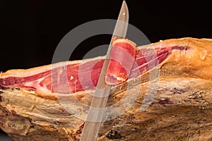 A knife cutting a spanish serrano ham photo