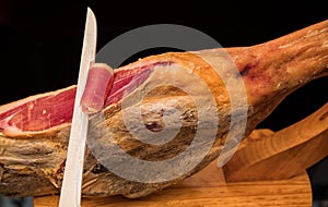 A knife cutting a spanish serrano ham photo