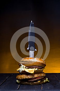 The knife is embedded in a burger. Hunting knife in a burger photo