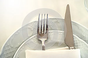 knife and fork in a folded napkin on two plate