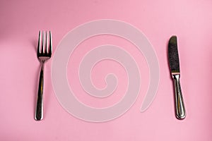 Knife and fork isolated on pastel pink background. Copy space banner