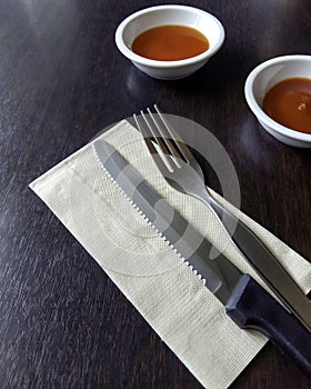 Knife and fork at napkin on wooden