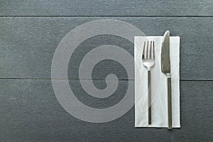 Knife and fork at napkin on wooden background