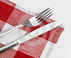 Knife and fork on red checked tablecloth