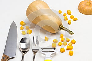 Knife, fork, spoon, peeler and sliced pumpkin pieces on the table