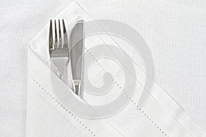 Knife and fork with white linen serviette