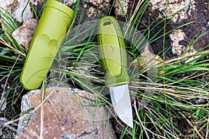 A knife with a green handle. Knife and plastic sheath. Horizontal frame.