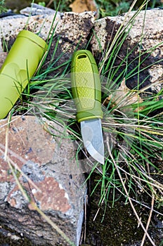 A knife with a green handle. Knife and plastic sheath. Vertical shot.