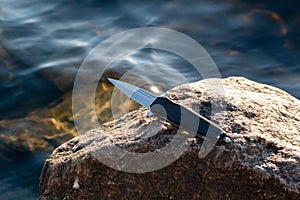Knife handle with cullet. Knife on the background of the river photo
