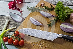 Knife with healthy food - vegetables, onion, salad, tomatoes, potato placed on a cutting board with wood background top view