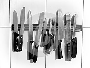 Knife magnet on the wall, many different knives; vintage, grunge, black and white concept