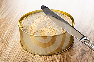 Knife on opened jar with sterilized cod caviar on wooden table