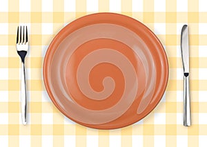 Knife, orange plate and fork on checked top view