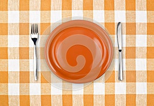 Knife, plate, fork on checked tablecloth