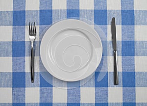 Knife, plate and fork checked tablecloth top view photo
