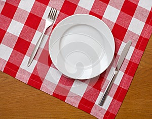 Knife, plate and fork on table with red tablecloth