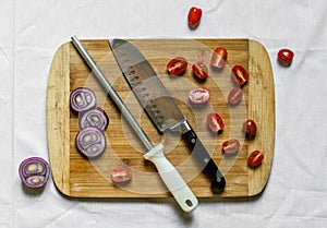 A knife sharpener and a chef knife on a cutting board with vegetables