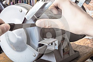 Knife sharpener and hand with blade on table, closeup