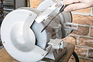 Knife sharpener and hand with blade on table, closeup