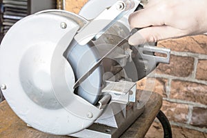 Knife sharpener and hand with blade on table, closeup