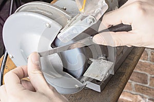 Knife sharpener and hand with blade on table, closeup