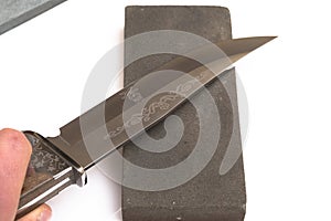 knife sharpening, knife on isolated white background with abrasive stone.