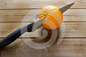 Knife slicing through an orange of the kitchen table before breakfast.