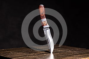 Knife stuck in a table on a black background