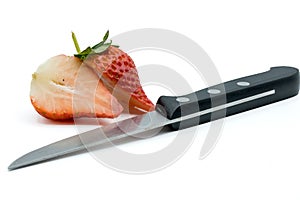 Knife with two halves of a sliced strawberry on a white background.